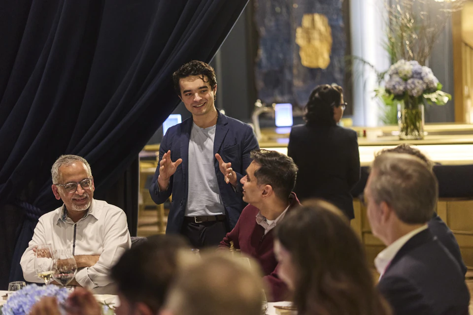 Isma échange avec les invités autour d’une table pendant une réception.