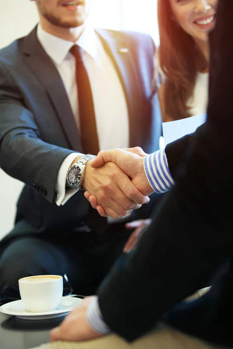 Attorney shaking hands with a client across a conference table