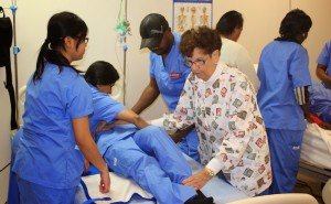 Healthcare aids attending to a patient on a medical bed.