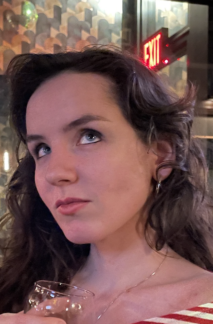 Portrait of a brunette woman in a red striped shirt from the shoulders up.