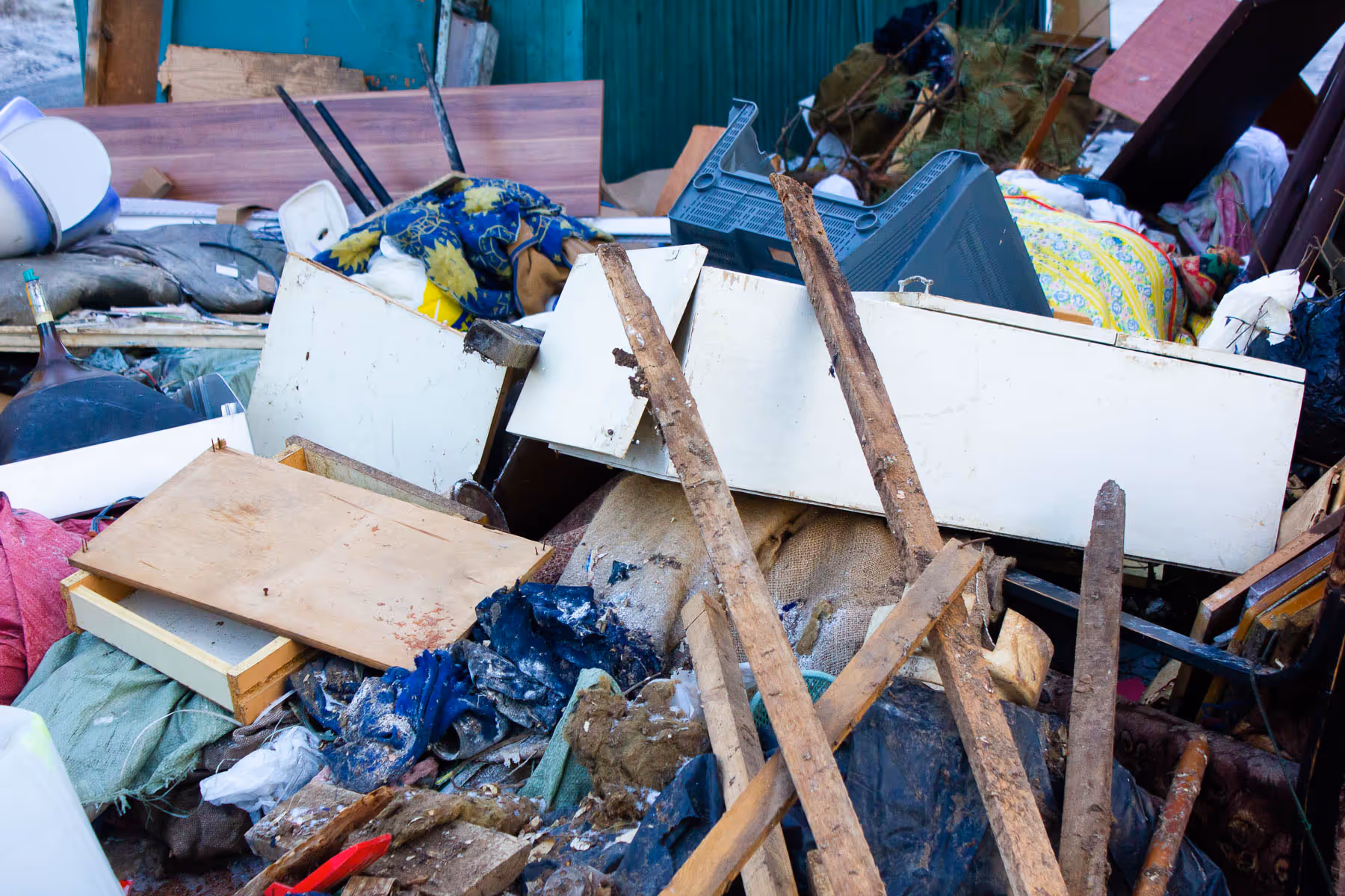 A pile of various debris, including wood, furniture pieces, and household items scattered outdoors.