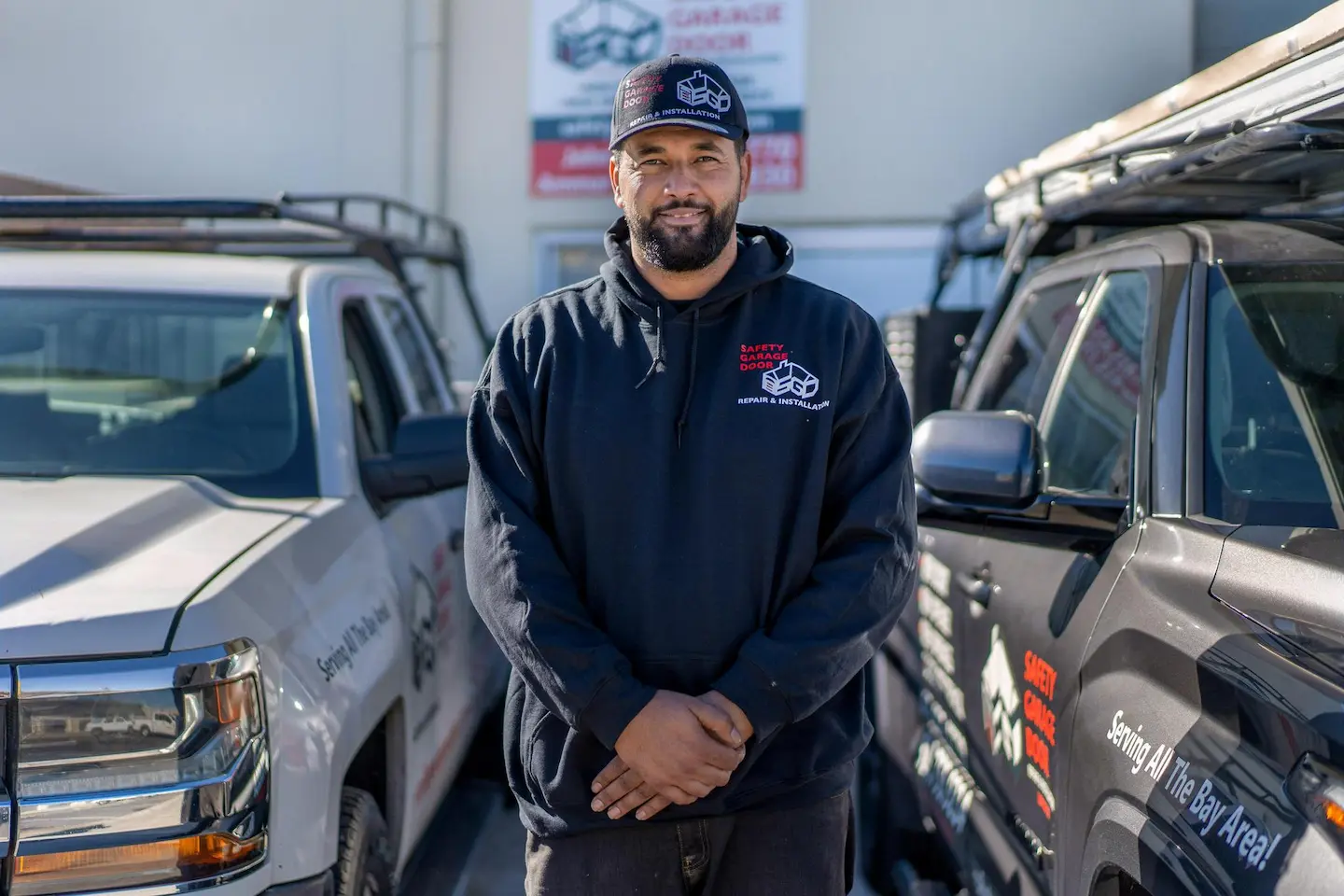 A man wearing a hat standing between two pickup trucks