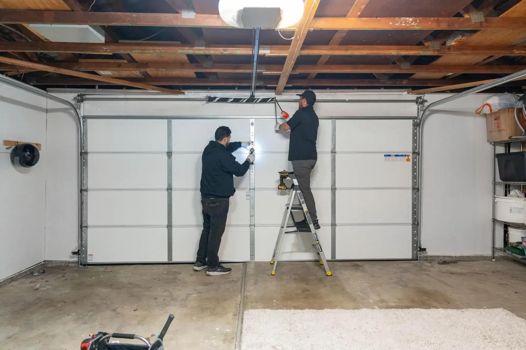 Two technicians working on a garage door.