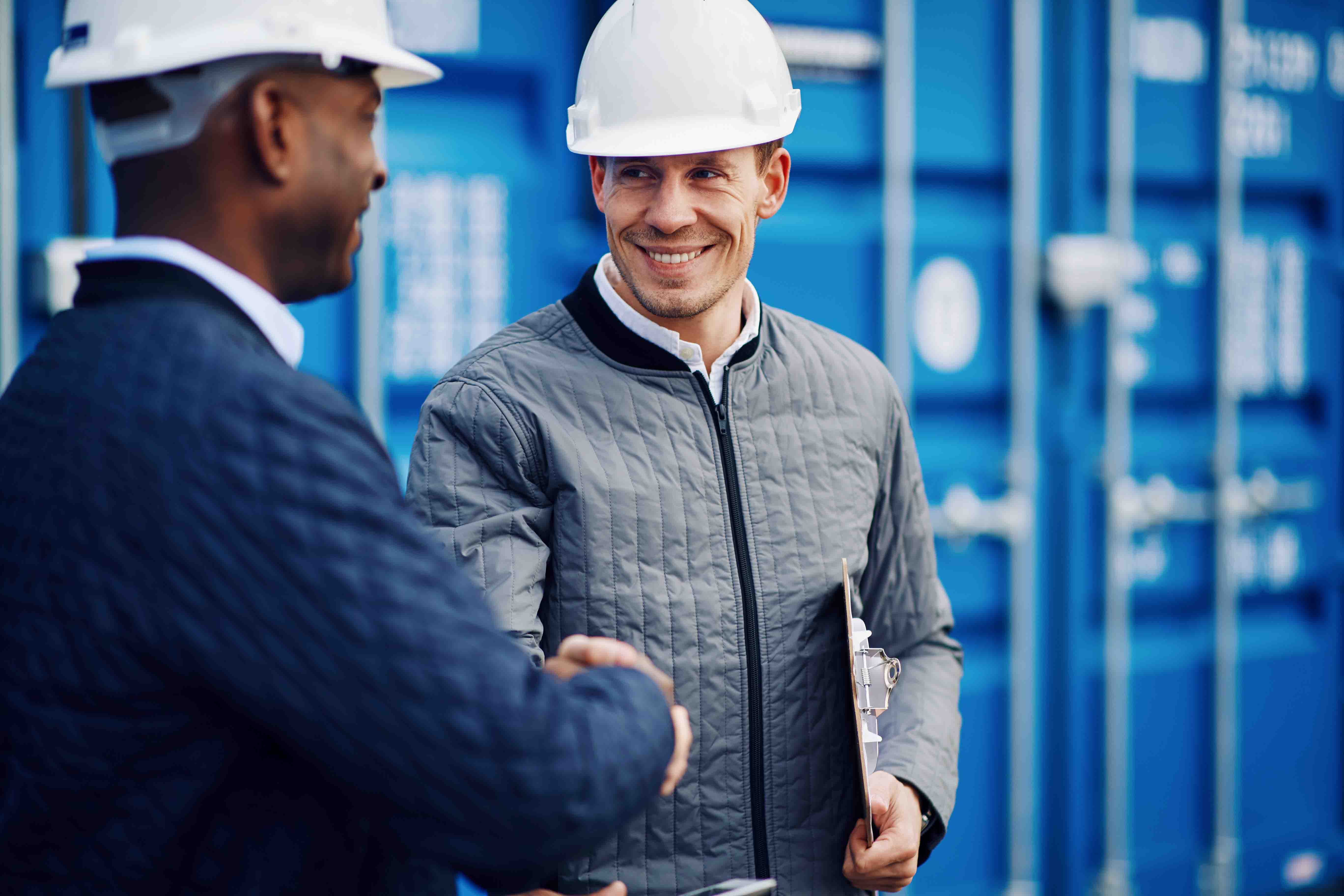 Two workmen smiling and shaking hands