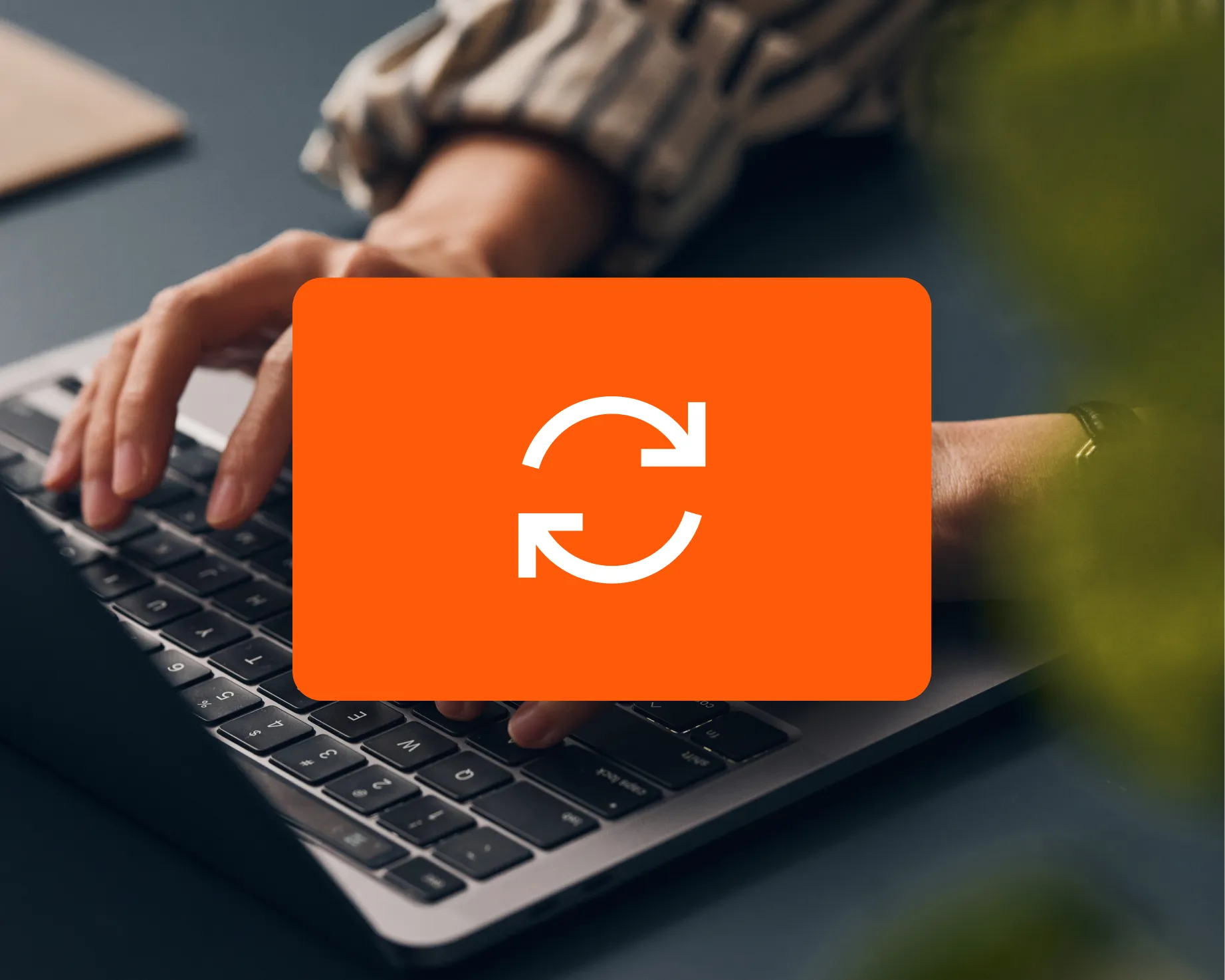 Hands typing on a laptop keyboard with a large orange sync icon overlayed in the center.