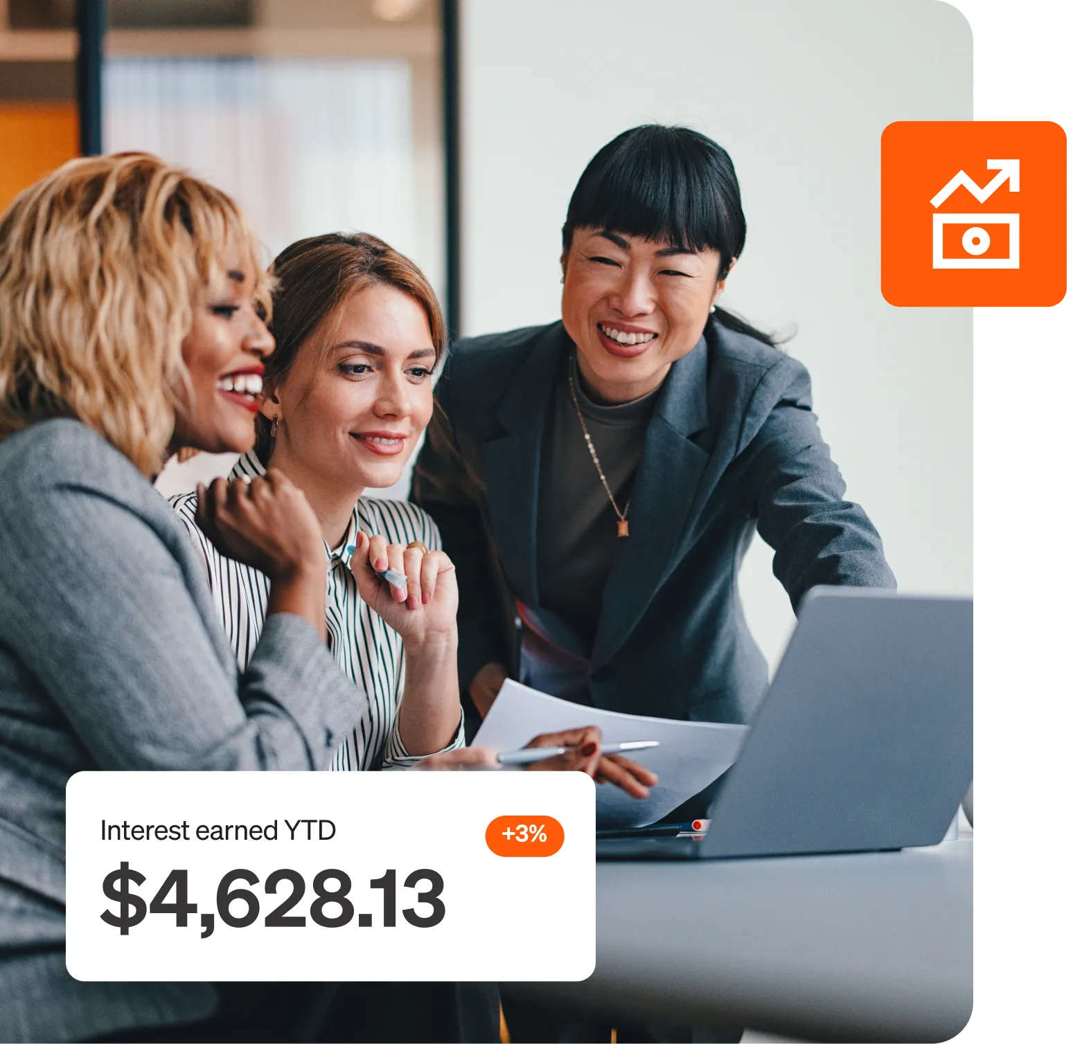 Three women smiling and looking at a laptop with a popup stating, "Interest earned ytd $4628.13".