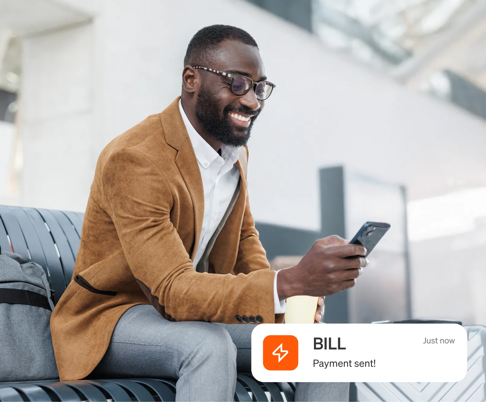 Man smiling at airport with phone and coffee; app message overlay reads "BILL Payment sent!"