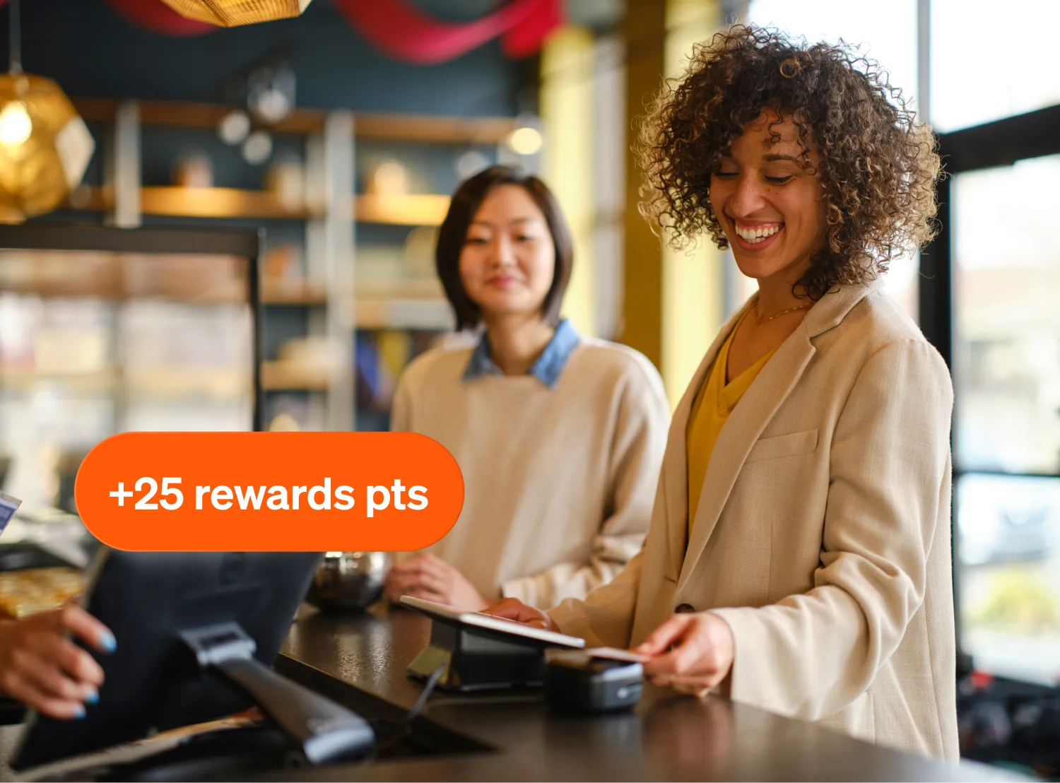 Two smiling women at a counter; one taps a card. An overlay reads "+25 rewards pts.