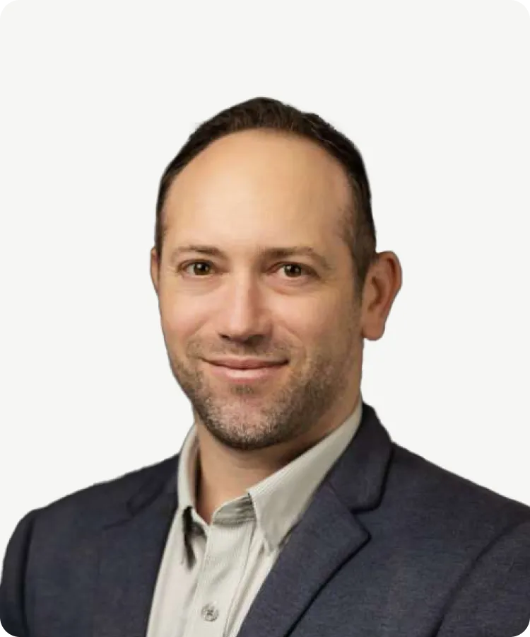 Smiling man in a blue blazer and light shirt, facing forward against a white background.