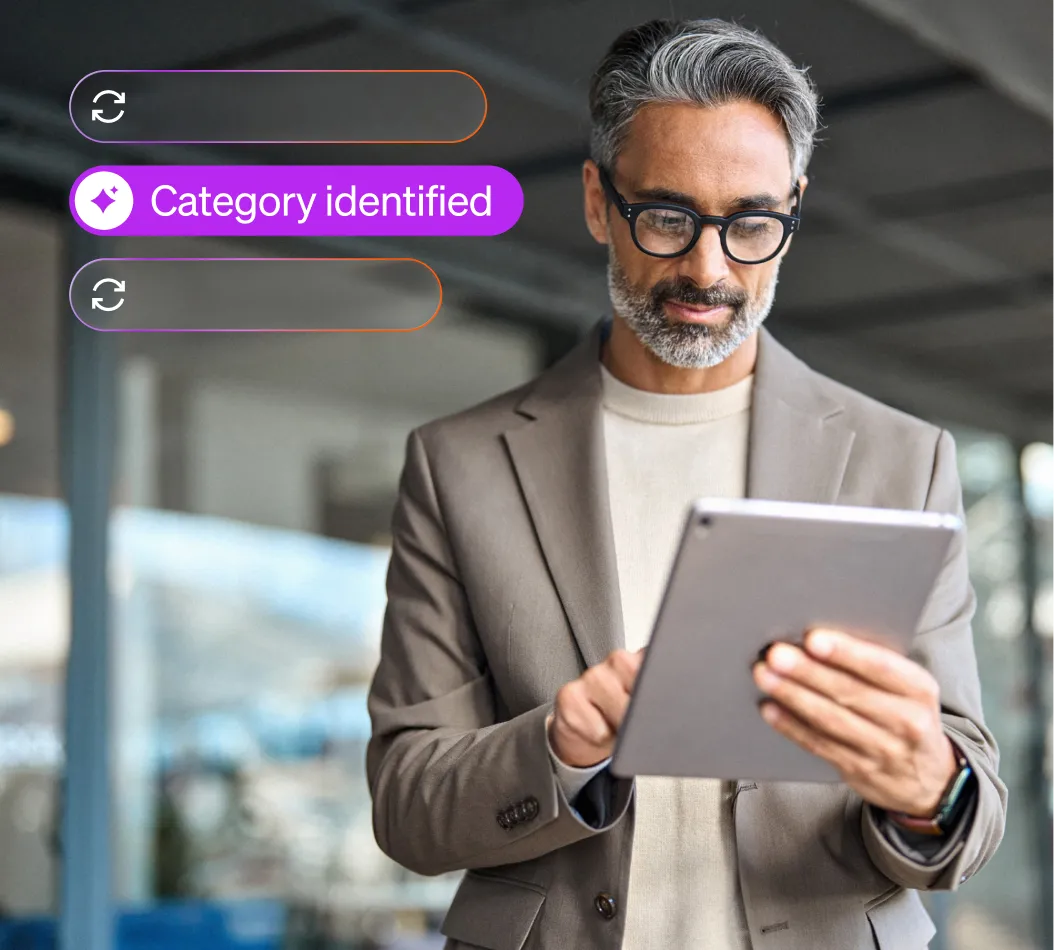 Man with salt-and-pepper hair and beard wearing glasses, a grey blazer, and a beige sweater uses a tablet with notification "Category identified".
