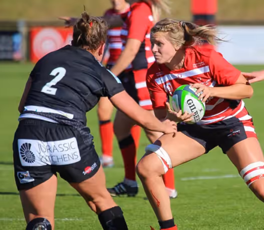 A group of women playing rugbyAI-generated content may be incorrect.