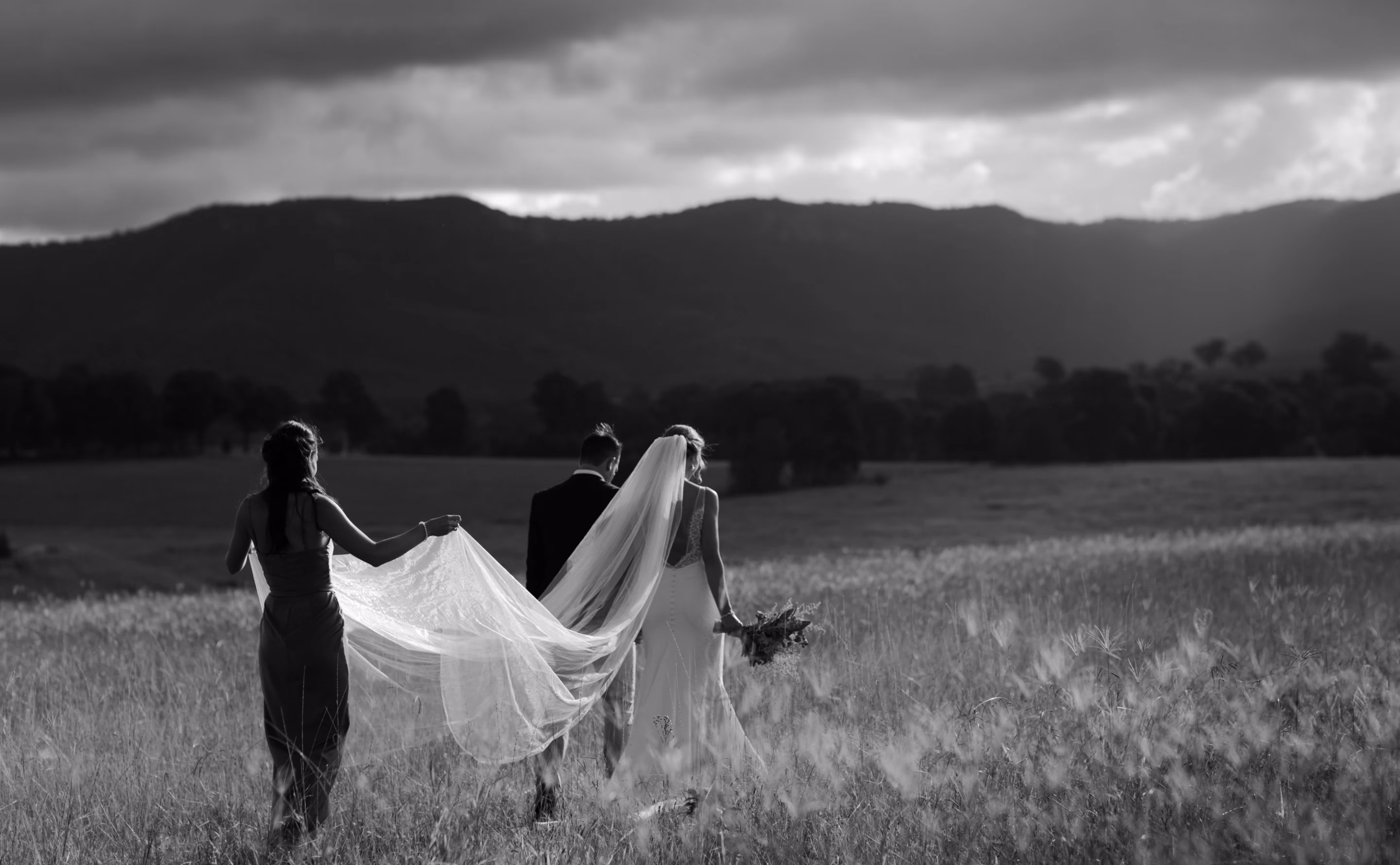 A black and white photo of a couple walking in a field