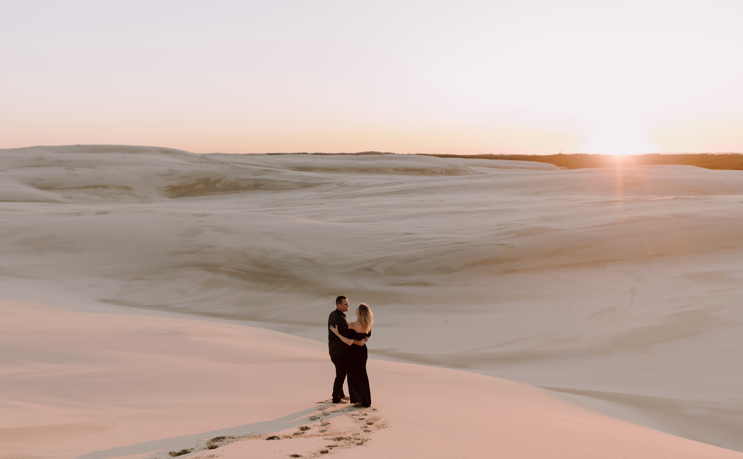 A couple standing in the sand dunes