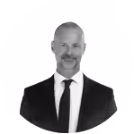 Black and white portrait of a bald man with a mustache and goatee wearing a suit and tie.