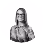 Smiling woman with glasses wearing a satin blouse against a white background.