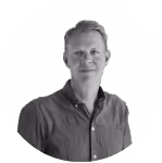 Portrait of a man with short hair wearing a buttoned dark shirt against a white background.