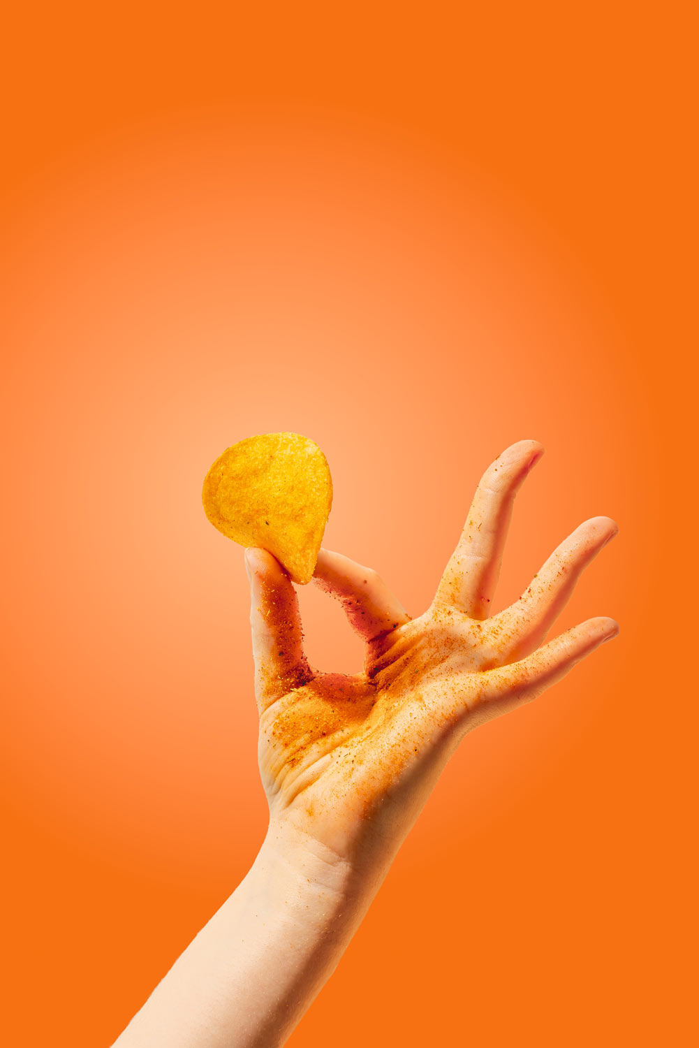 Pacote de batatas fritas sabor a molho de francesinha da marca Londrina - Mão segurando uma batata frita temperada com pó vermelho.