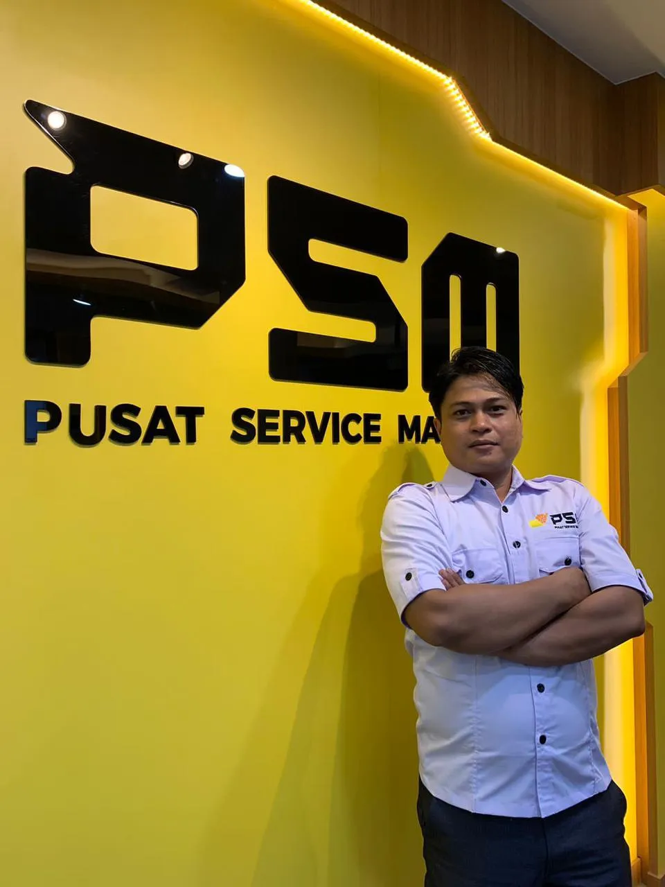 Teknisi Paling Senior Pusat Service Macbook bali yang bersertifikasi BNSP didepan logo PSM di Bali