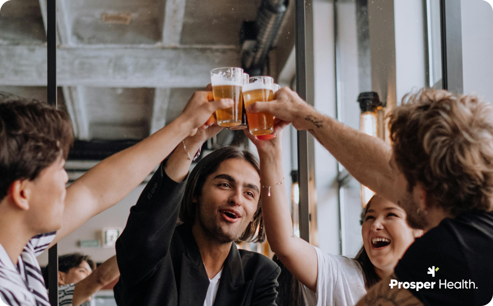 male friends at a bar raising up and cheering their glasses of beer