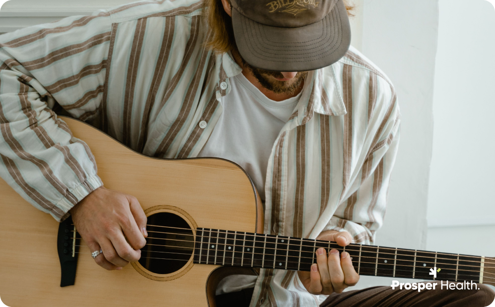 Man in a striped shirt playing an acoustic guitar