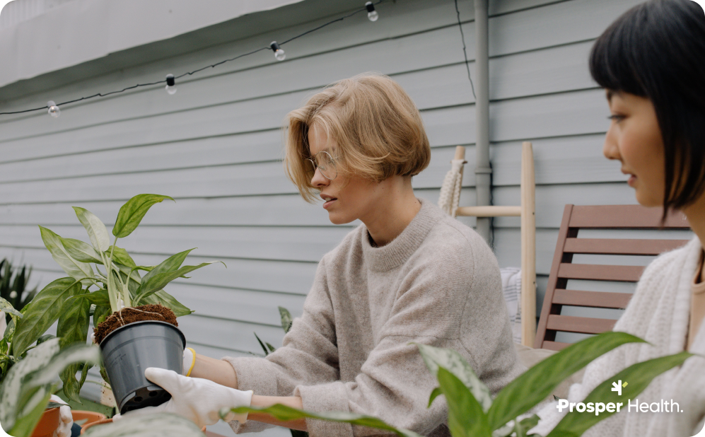 two women work with potted plants