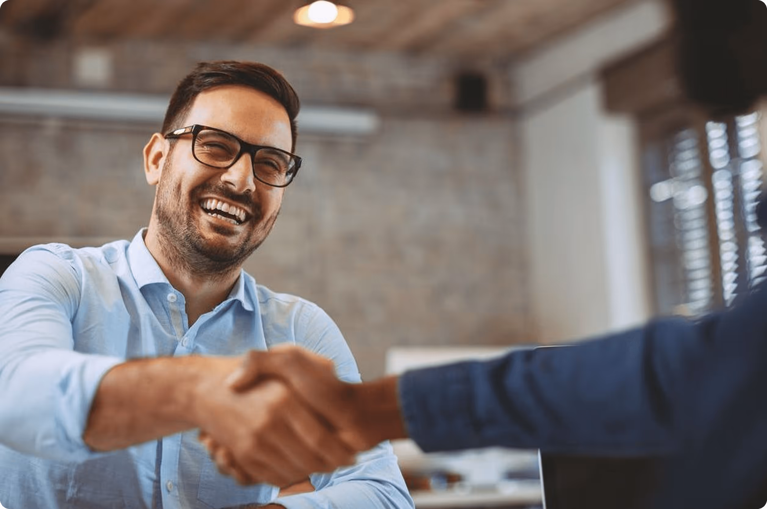 A man shaking hands with another man in a blue shirt.