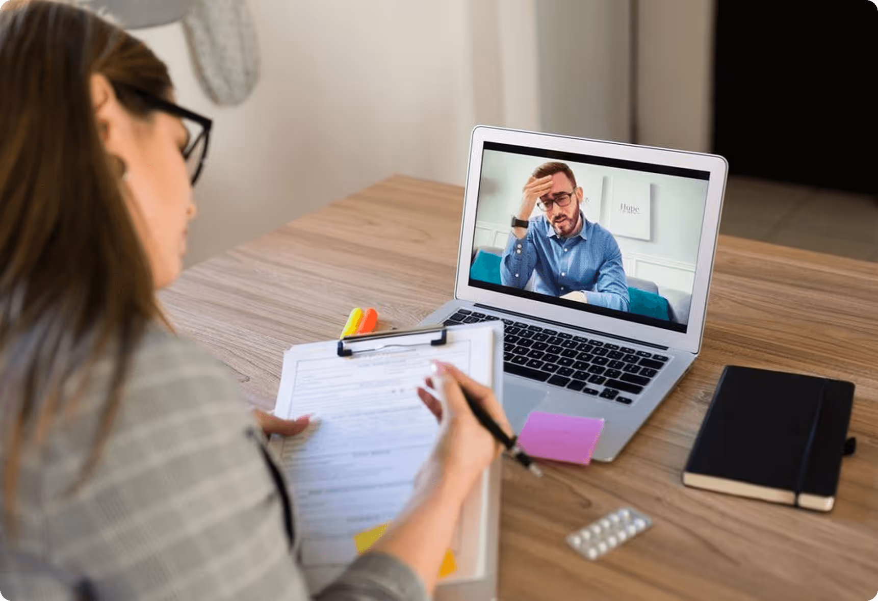 A woman sitting at a desk in front of a laptop.