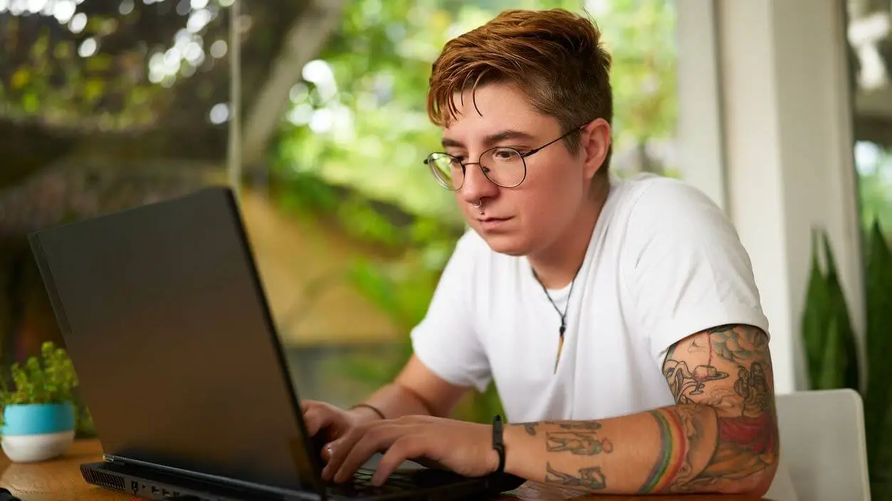 A man sitting at a table using a laptop computer.