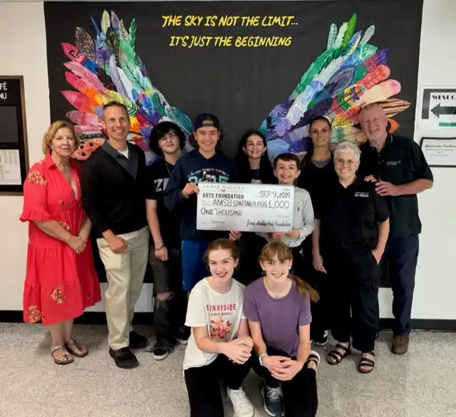 The Jamie A. Hulley Arts Foundation presents a $1000 check to the Amity Spartan Players for their Wonka Jr. production, featuring students.