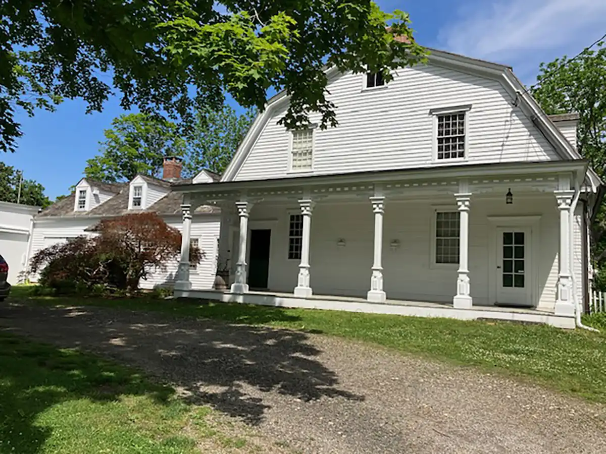 Historic white Darling Farmstead and History Museum building with gambrel roof, clapboard siding, and covered porch with decorative columns.