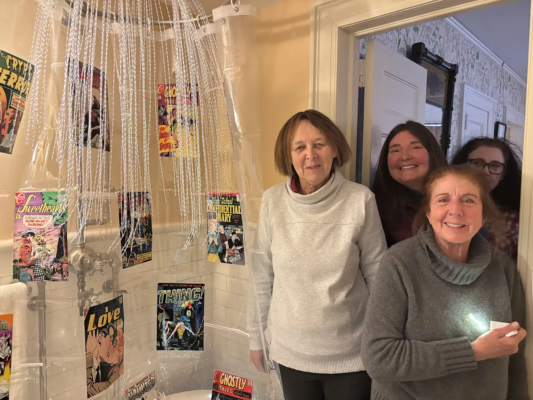 Garden Club of Woodbridge members pose with a shower curtain decorated with vintage Charlton Comics covers at the Osborne Homestead Museum holiday tour.