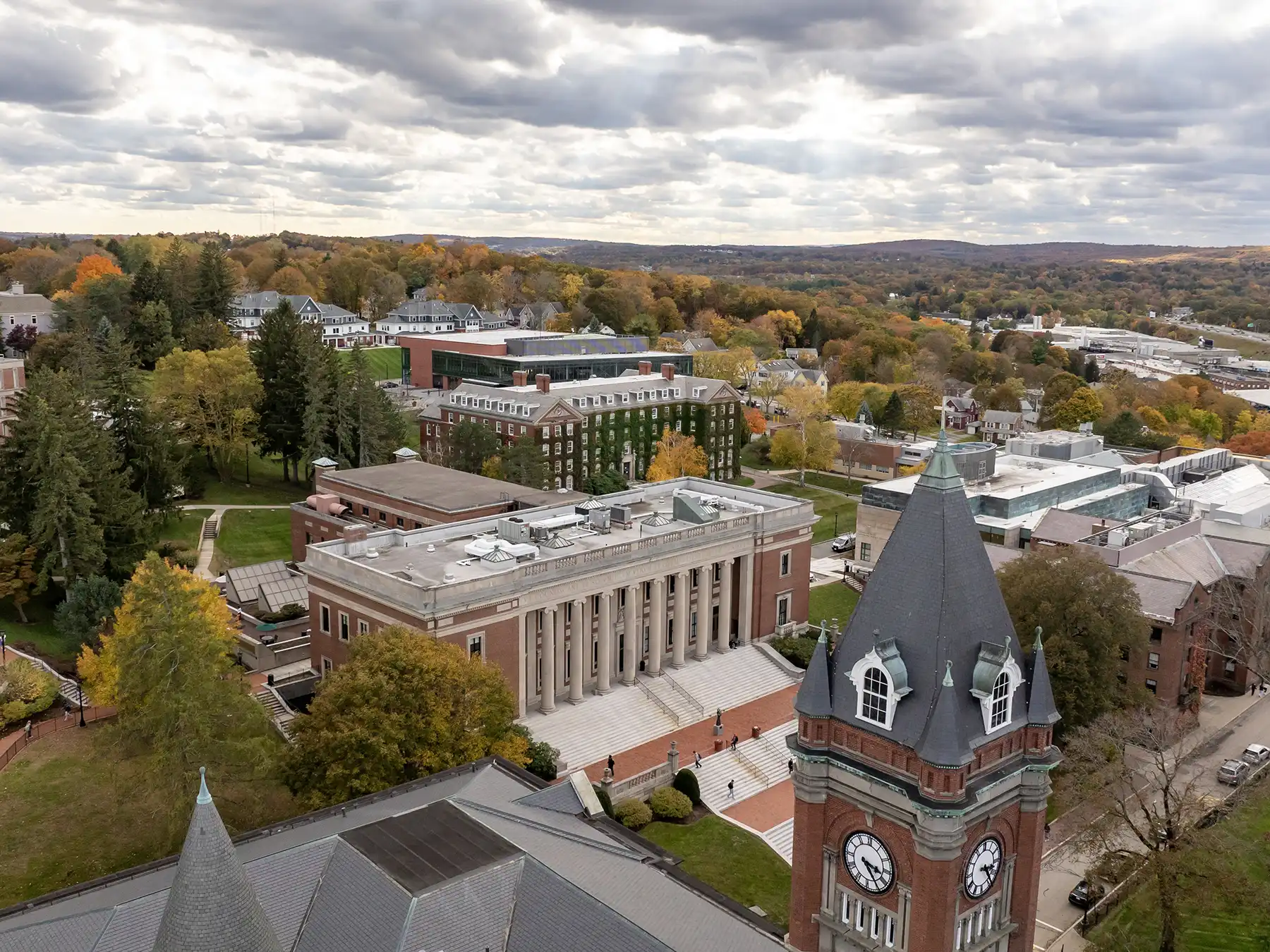 Aerial view of the College of the Holy Cross campus in Worcester, MA, featuring the iconic clock tower and academic buildings surrounded by autumn foliage.