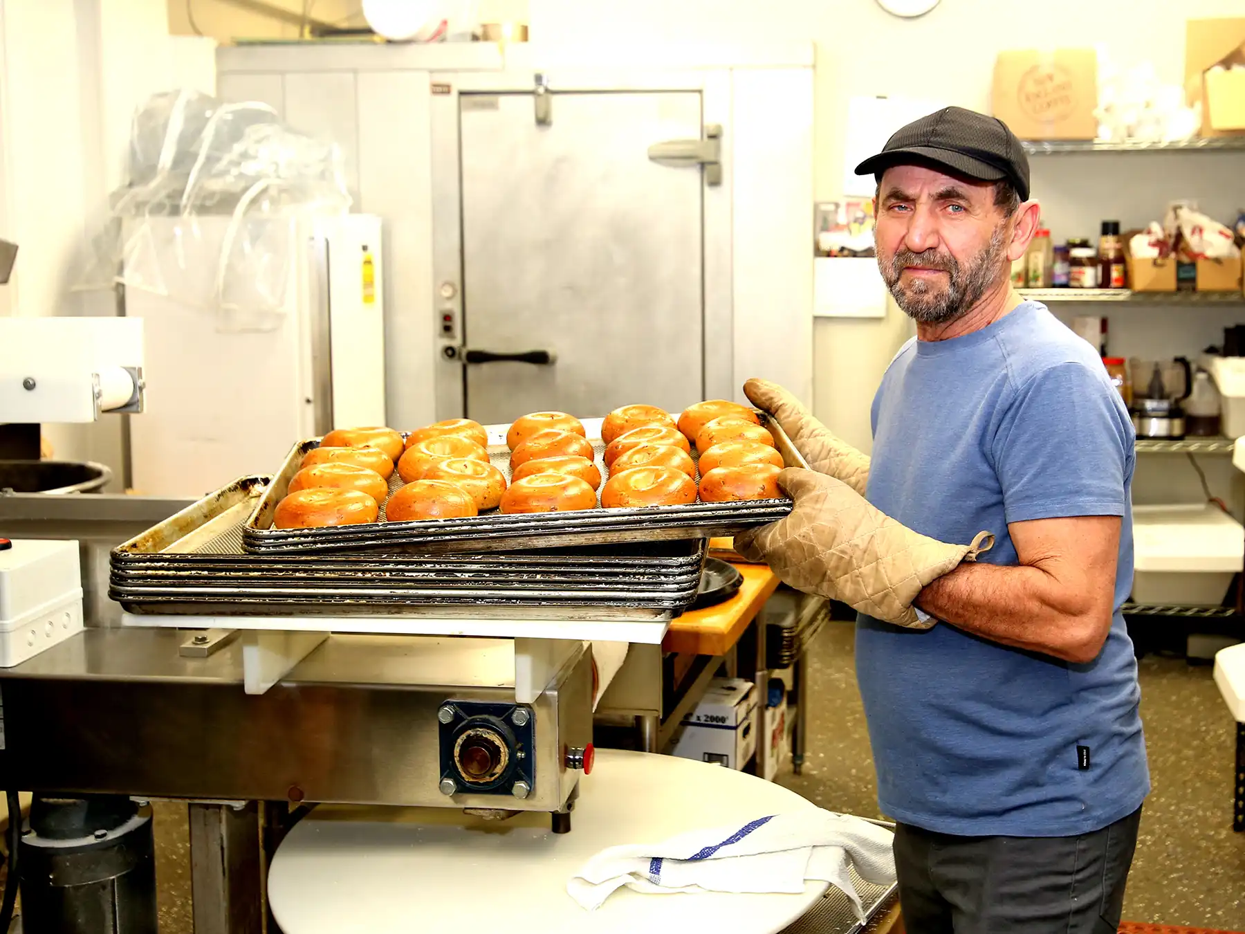 Daily Bagel owner Mike Vinca proudly holds a tray of freshly baked, golden brown bagels in the kitchen of his new Woodbridge bakery shop.