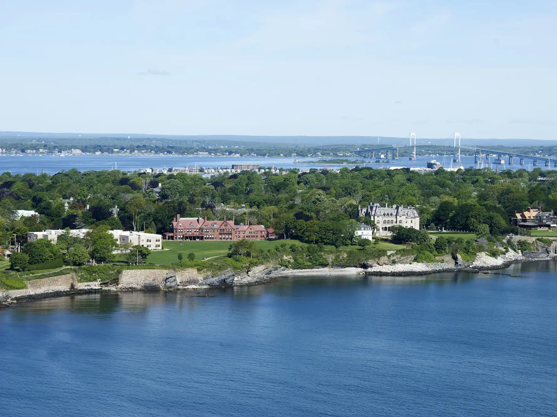 Aerial view of the Salve Regina University oceanfront campus buildings along the coastline in Newport Rhode Island with a bridge.