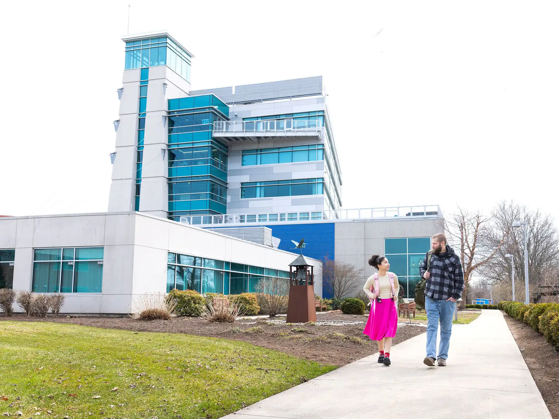 Two students chat while walking outside the modern glass and steel building at Goodwin University on Riverside Drive in East Hartford, CT.