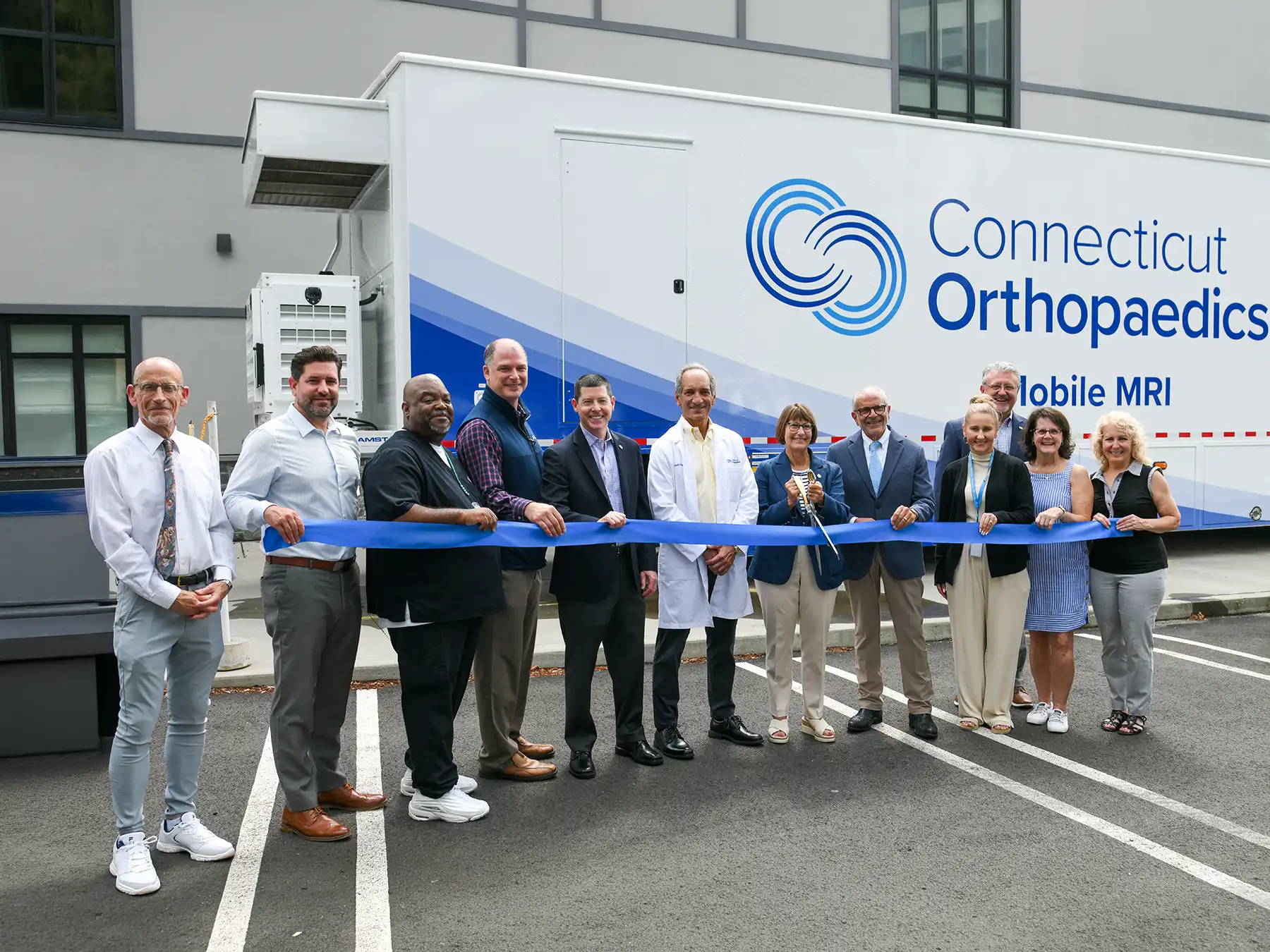 Connecticut Orthopaedics CEO Susan Bader and local officials cut a blue ribbon to celebrate the launch of the new Mobile MRI unit.