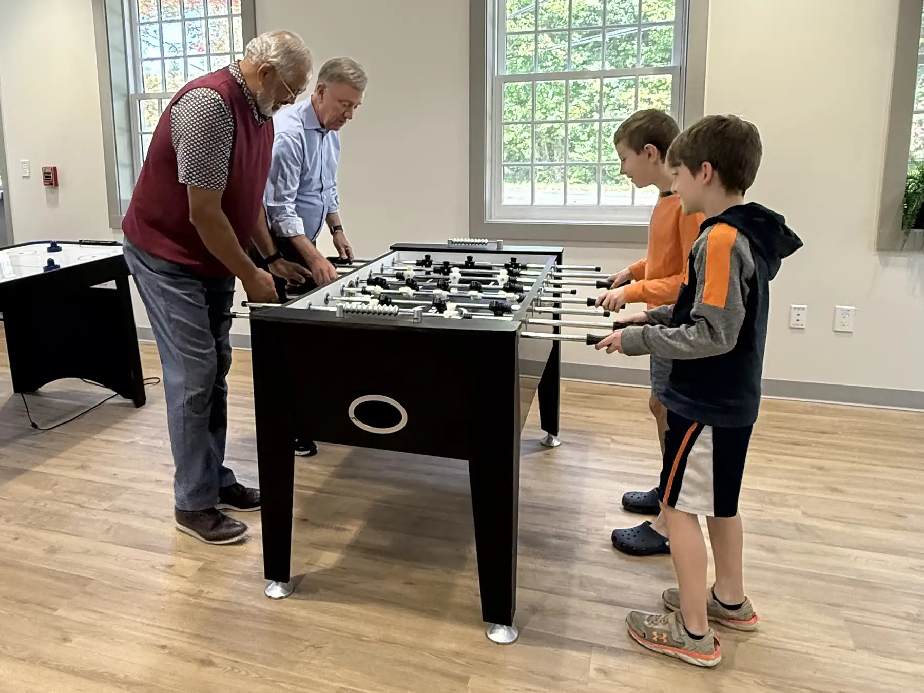 Governor Ned Lamont and First Selectman Mica Cardozo play foosball with young residents inside the Woodbridge Community & Cultural Center game room.
