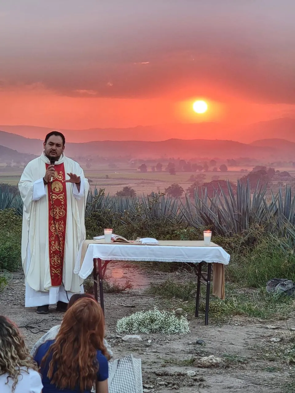 Un sacerdote en el campo abierto dando una homilía.