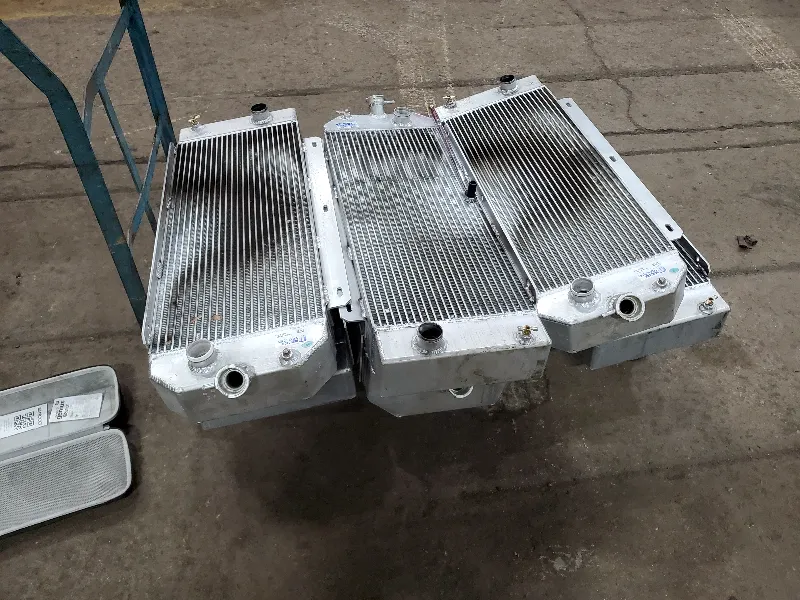 Three aluminum radiators lined up on a shop floor, prepped for heavy-duty cooling system service.