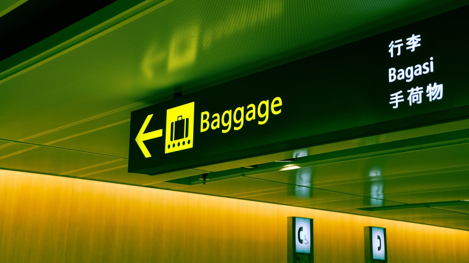 An illuminated airport sign reading Baggage in English, Chinese, Indonesian and Japanese