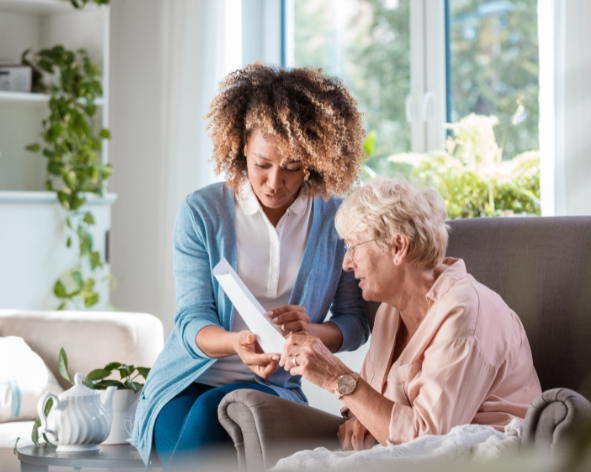 Woman reading document to elderly woman on couch — elk Marketing