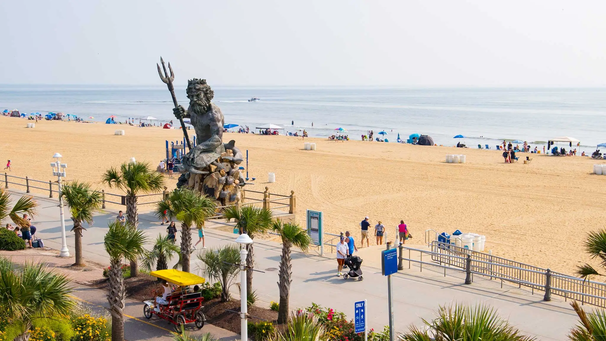 King Neptune statue on Virginia Beach boardwalk overlooking the sandy beach and ocean.