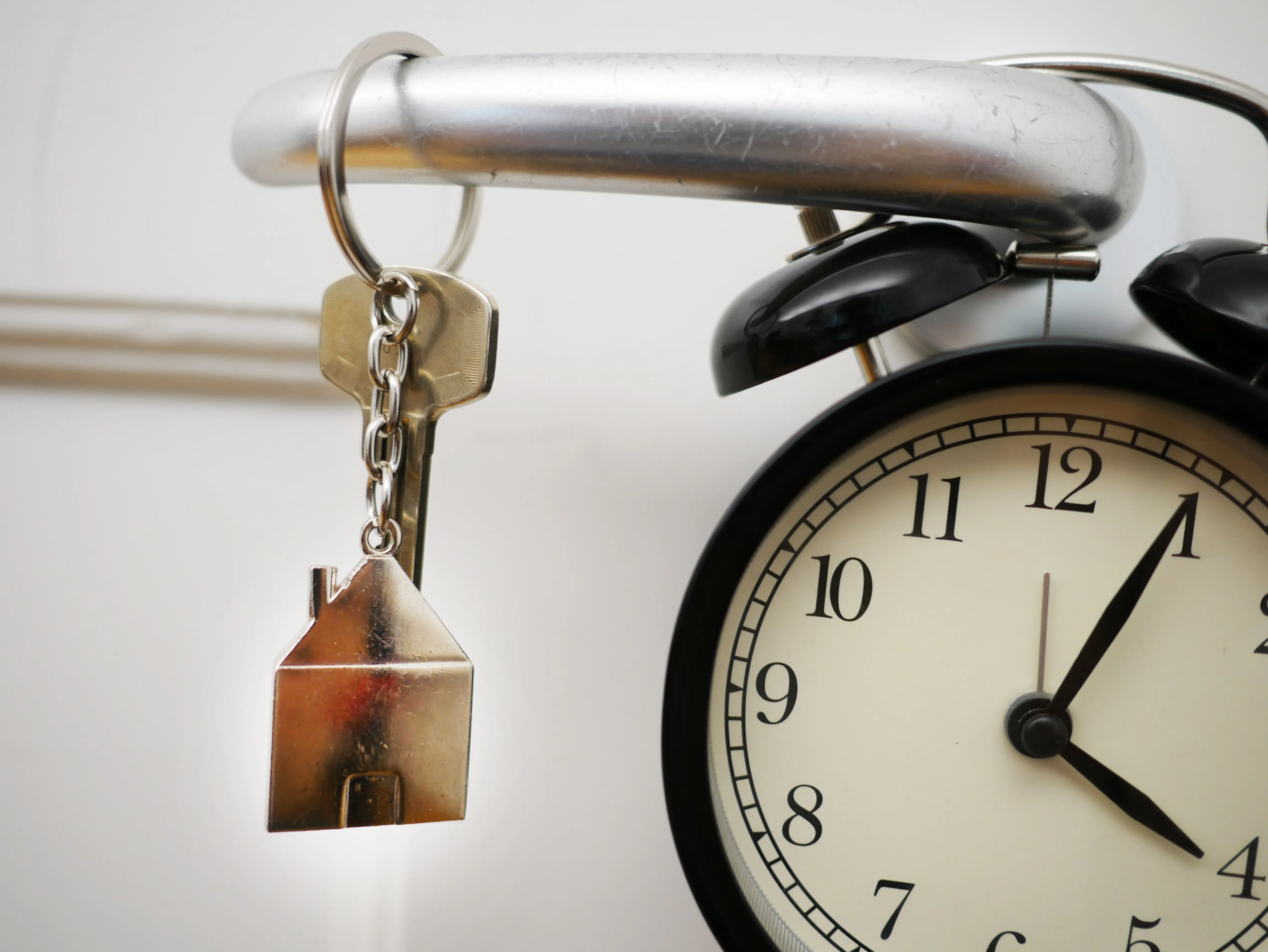A alarm clock hanged in a door knob with keys in front