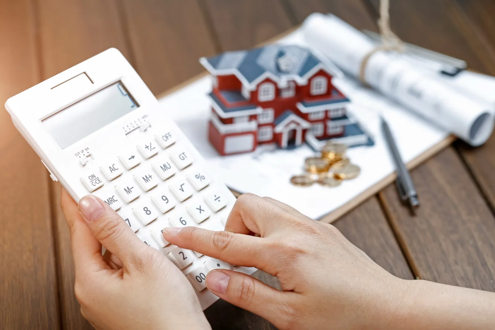 A picture of a hand using a calculator with a notebook in a desk