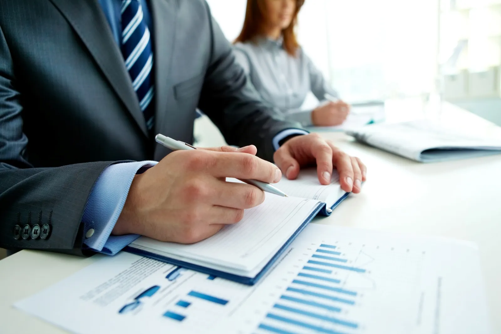 A picture of two employee working on a notebook in their desks