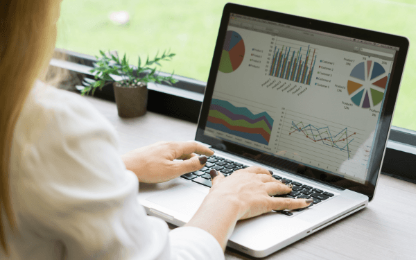 Person arbeitet an einem Laptop und analysiert Datenvisualisierungen wie Diagramme und Grafiken auf dem Bildschirm.