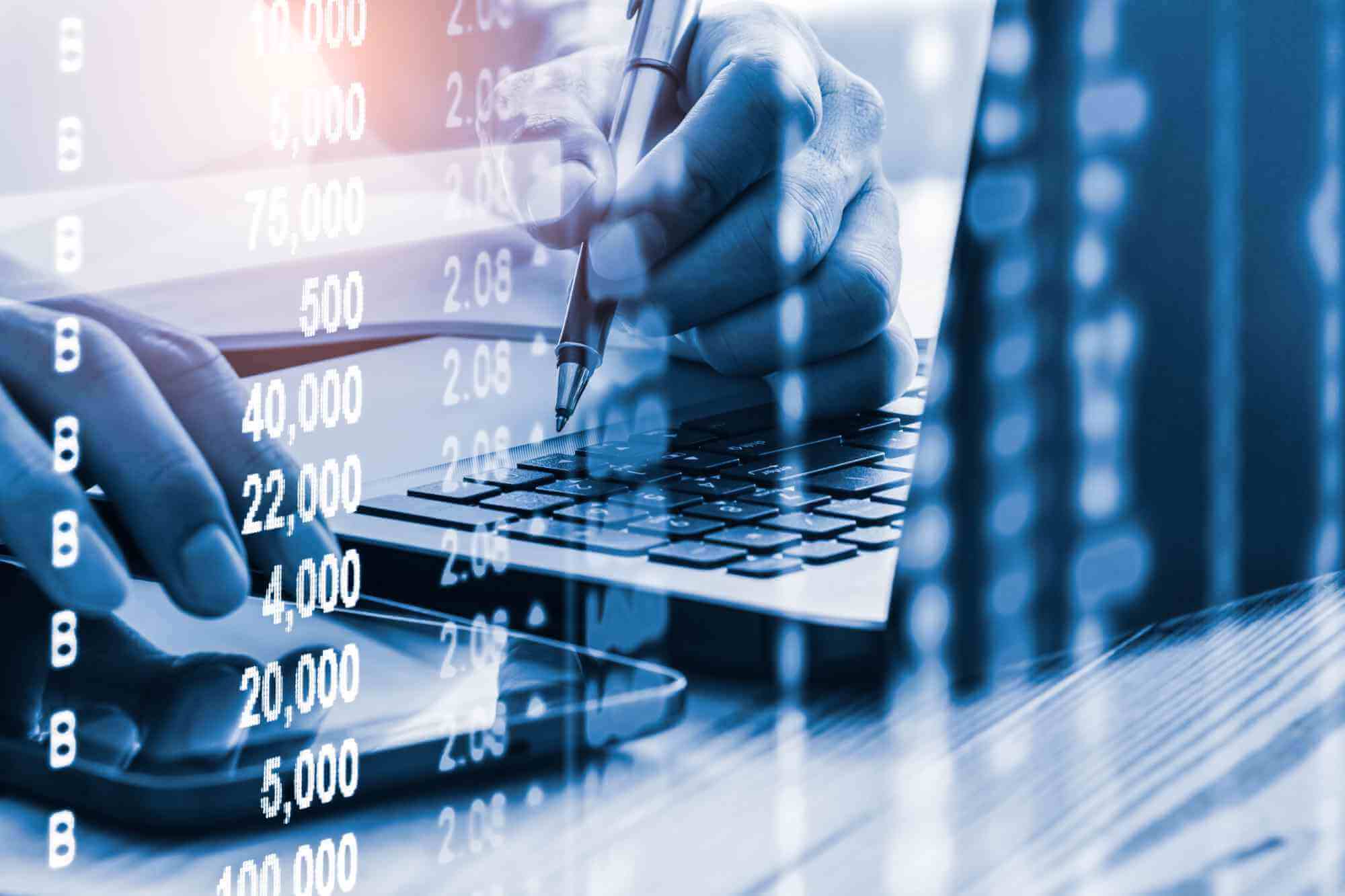 Person nutzt Laptop und Smartphone zur Analyse von Finanz- und Geschäftsdaten mit eingeblendeten Zahlen und Kennzahlen.