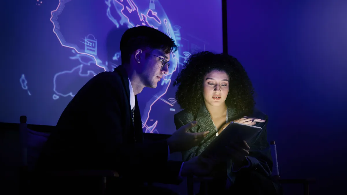 Two procurement professionals reviewing AI-driven analytics on a tablet in front of a digital world map