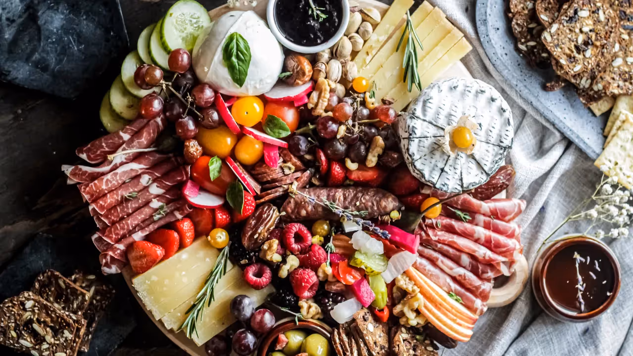 A bird's eye view of a charcuterie board filled with meats, cheeses and fruits.
