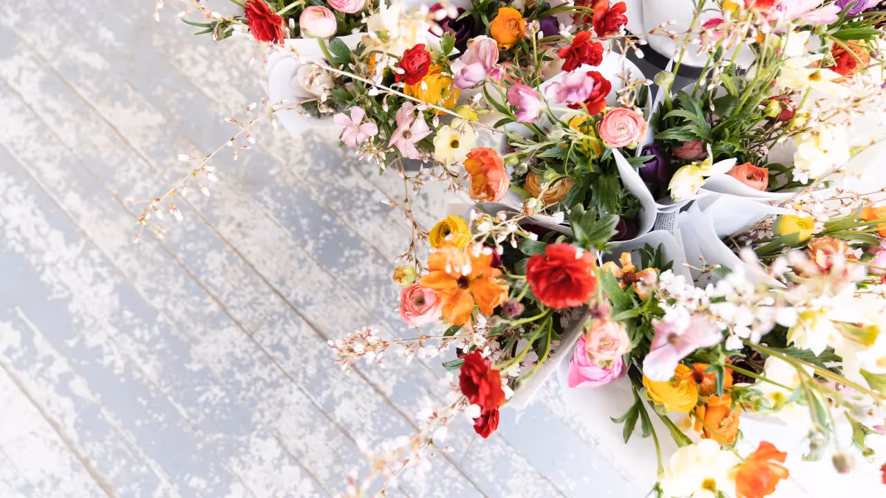 Colourful bouquets of spring flowers sitting on a wooden floor.